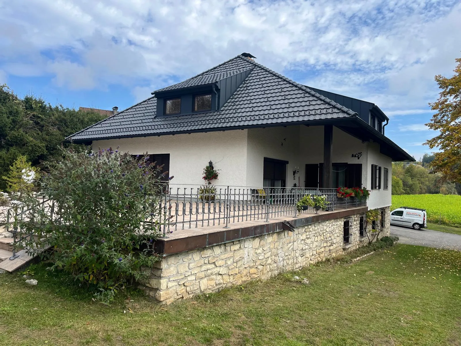 Wohnhaus mit dunklem Walmdach, Gauben und umlaufender Dachrinne
