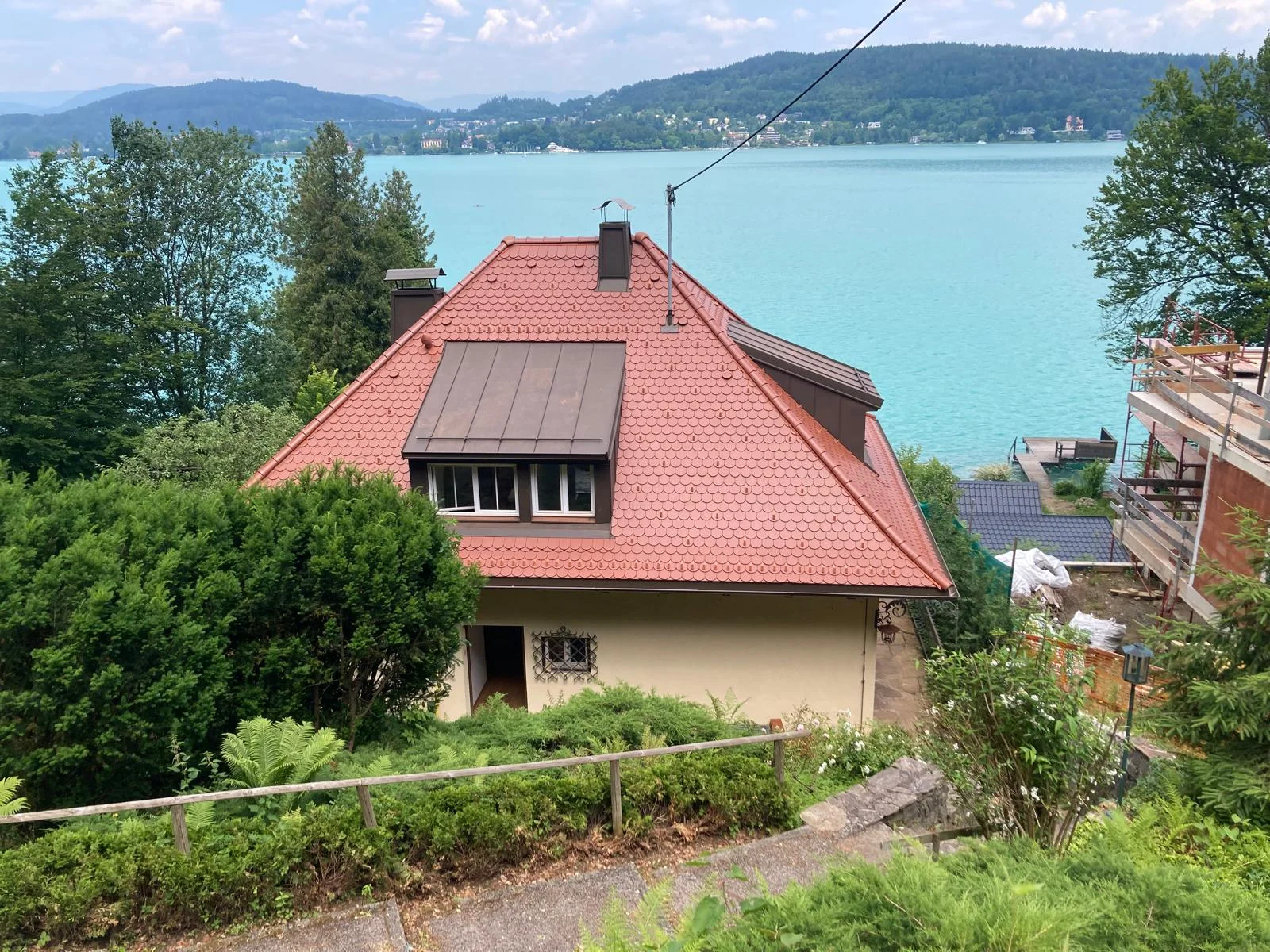 Privathaus am Wörthersee mit roter Rundschnittdeckung, metallverkleideter Gaube und Kaminen