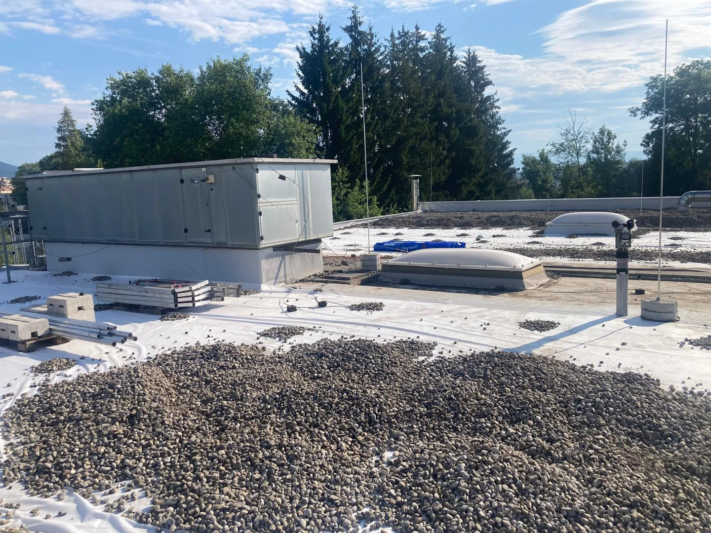 Industrieflachdach in Klagenfurt mit Kiesauflage, Lichtkuppeln und einem großen Technikaufbau während der Arbeiten